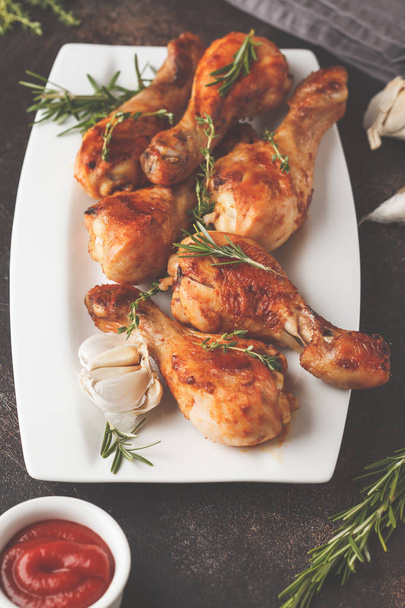 Grilled spicy chicken legs baked with garlic, rosemary and thyme in white plate on dark background. - Fotografie, Obrázek