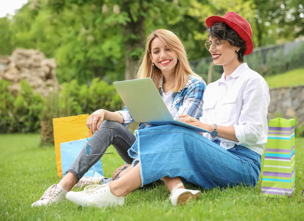 Young women in stylish clothes with laptop outdoors - Фото, изображение