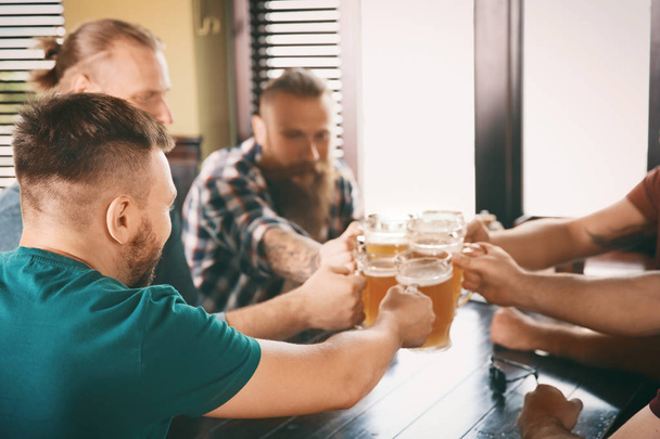Friends clinking glasses with beer in pub - Фото, зображення