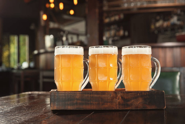 Bicchieri di birra saporita su tavolo di legno in bar
 - Foto, immagini