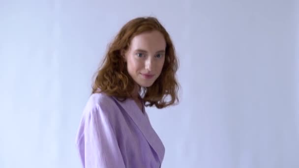 alegre chica positiva posando para la cámara en un traje púrpura sobre un fondo blanco
 - Metraje, vídeo