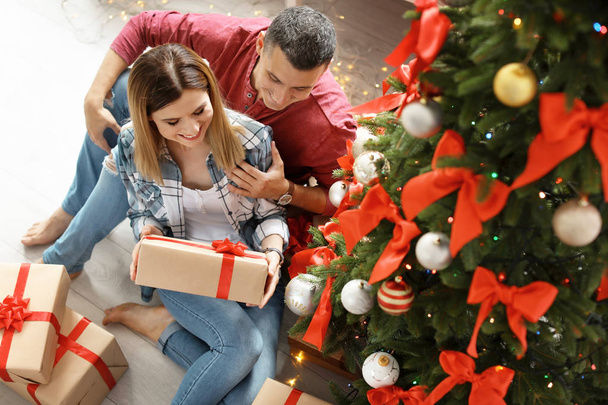Young couple with Christmas gifts at home - Foto, Imagen