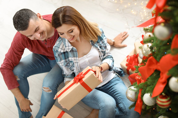 Young couple with Christmas gift at home - Фото, изображение