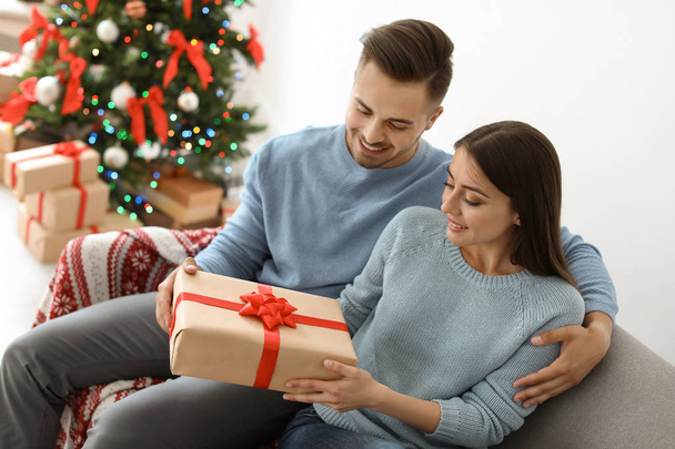 Young couple with Christmas gift at home - Photo, image