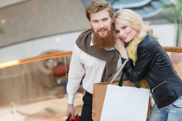 Happy beautiful young couple with shopping bags in mall - Fotografie, Obrázek
