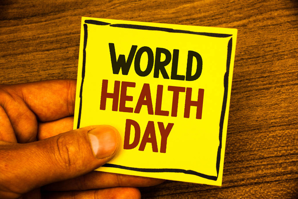 Word writing text World Health Day. Business concept for Special Date for Healthy Activities Care Prevention Man holding yellow paper ideas black red letters frame wooden background - Photo, Image