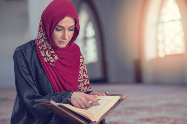 Mujer musulmana leyendo el Corán o el Corán vestida con un vestido tradicional en la mezquita - Foto, Imagen