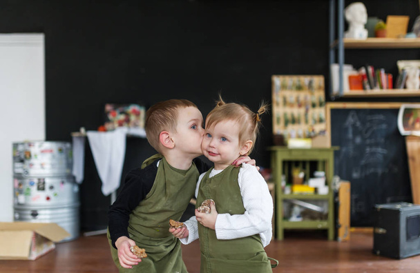 Маленький брат цілує свою гарну сестру в творчому класі. Концепція ранньої дитячої освіти, таланту, щасливої сім'ї або батьківства
. - Фото, зображення