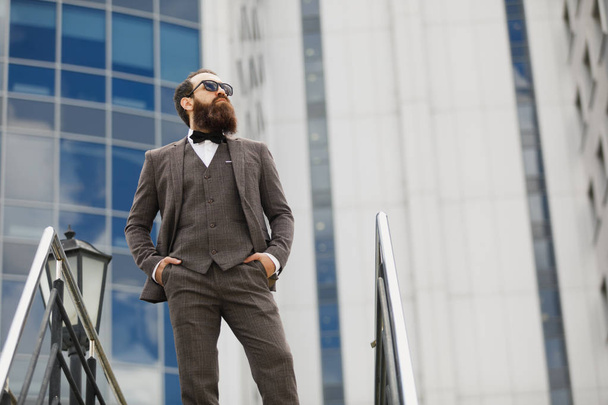bearded man in sunglasses with a very interesting look with cityscape in the background - Photo, image