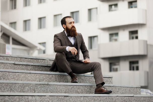 Modern businessman. Confident young man in full suit looking away while standing outdoors with cityscape in the background - Фото, зображення