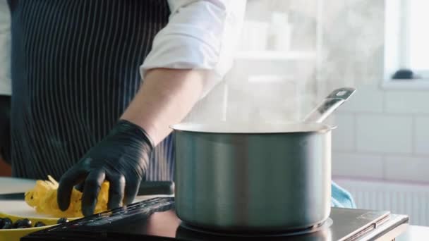 Close-up van chef-kok legt een pasta in een dampende pan op een fornuis - Video