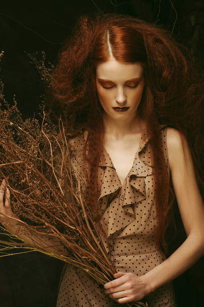Beauty and art concept: Young woman with bright make up with dry branches - Foto, afbeelding