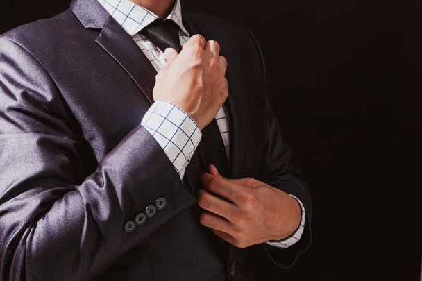 Empresario ajustando su traje sobre fondo negro
 - Foto, imagen