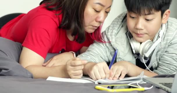 Asian mother helps his young son while the boy is doing his homework at home. - Footage, Video