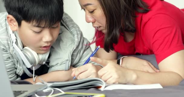 Matka pomaga jego młody syn, podczas gdy chłopak robi swoją pracę domową w domu. - Materiał filmowy, wideo