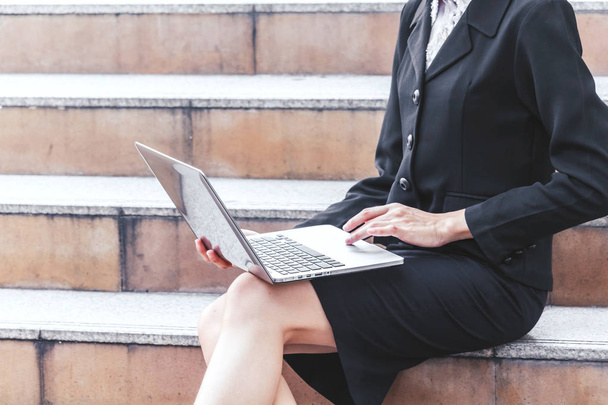 Femme d'affaires assise sur les escaliers et utilisant un ordinateur portable
 - Photo, image