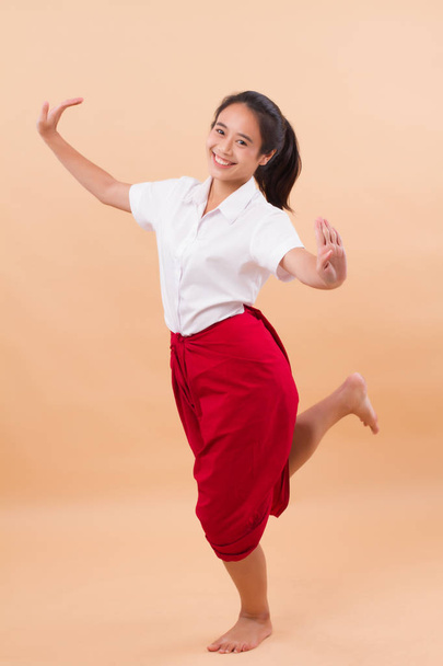 Thai performance art, woman dancer student dancing in traditional red loincloth; studio portrait of woman dancer in asian Thai traditional elegant dance move; young adult asian woman dancer model - Photo, Image
