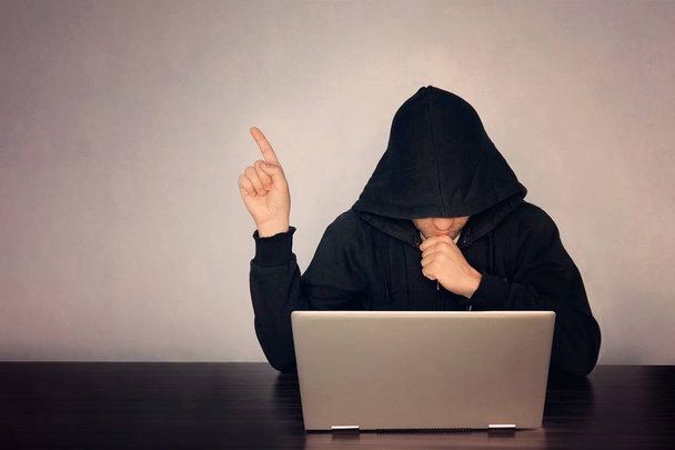 Хакер з капюшоном перед своїм комп'ютером Показати пальцем. Темні обличчя. з капюшоном .technology концепцію, хакер вказує пальцем на порожнє місце для тексту - Фото, зображення