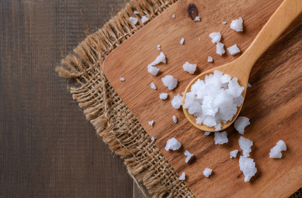 Sea salt in wood spoon on wood block and wood table background, top view and copy space - Foto, Imagen