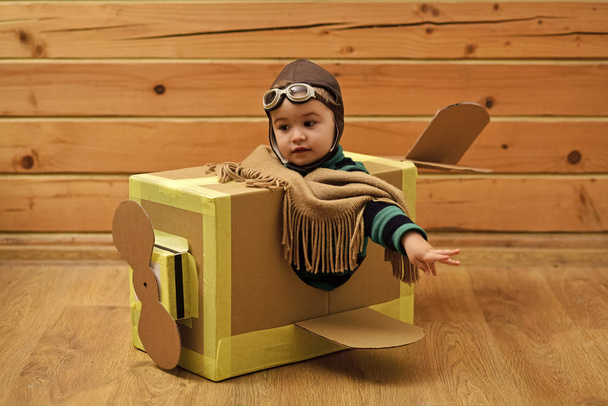Childhood dream imagination concept . Little cute boy playing with a cardboard airplane. - Fotó, kép