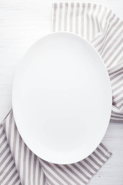 Placa ovalada blanca vacía sobre mesa de madera
 - Foto, Imagen