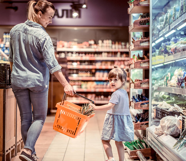 Mamá y su hija están de compras en el supermercado, el concepto de relaciones familiares y alimentación saludable
 - Foto, imagen