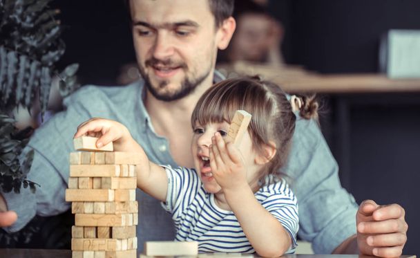 Dad and daughter play a game at a table in a cafe, celebrate his father's day, family values - Fotó, kép