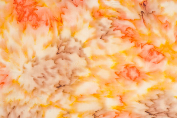 Textuur, achtergrond, patroon. Zijde stof met een wazig rood geel patroon. Geel, rood en crème bloemen op wit - Foto, afbeelding