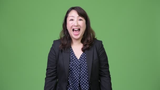 Érett boldog ázsiai üzletasszony emelt ököllel - Felvétel, videó
