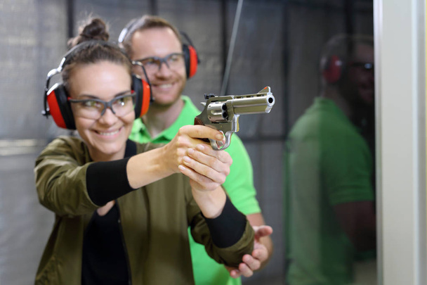 Shooting training. The woman shoots from the gun at the shooting range under the supervision of an instructor. - Photo, image