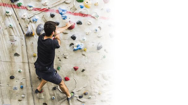 Un hombre practicando escalada en roca en paredes artificiales en interiores. Estilo de vida activo y concepto de bouldering con espacio de copia
 - Foto, Imagen