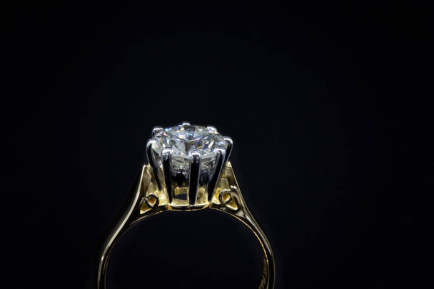Um grande diamante solitário colocado em um anel de ouro amarelo, isolado em um fundo preto
 - Foto, Imagem