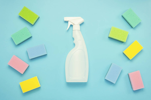 Accessories for cleaning, cleaning sponges lie on both sides and a cleaning spray in the middle on a blue background. cleaning service concept. Flat lay, Top view. - Photo, image