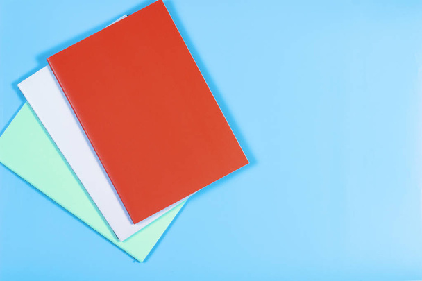 Cuadernos coloridos sobre fondo azul
 - Foto, imagen