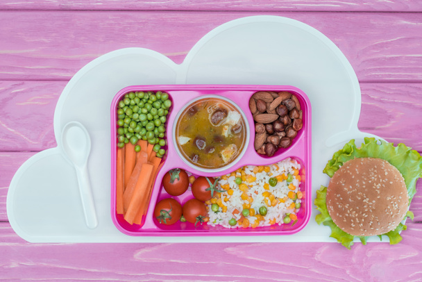 top view of tray with kids lunch for school and burger on pink table - Valokuva, kuva