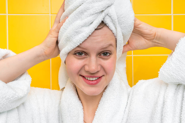 Красивая улыбающаяся женщина в халате с полотенцем на голове - Фото, изображение