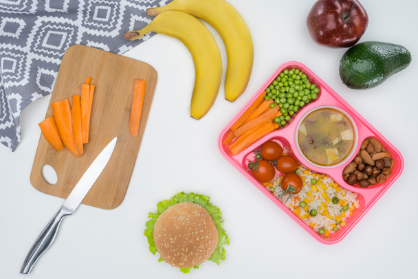 vista superior de la bandeja con almuerzo para niños para la escuela y tabla de cortar aislado en blanco
 - Foto, Imagen