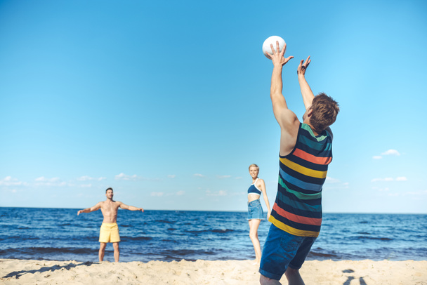 jeunes amis jouant au volley-ball ensemble sur une plage de sable
 - Photo, image