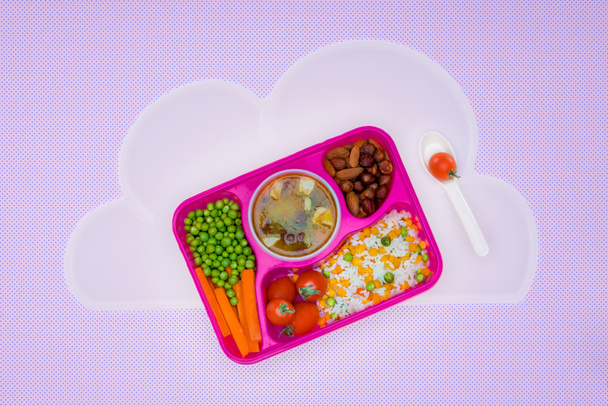vista superior de la bandeja con almuerzo para niños para la escuela en servilleta aislada en violeta
 - Foto, imagen
