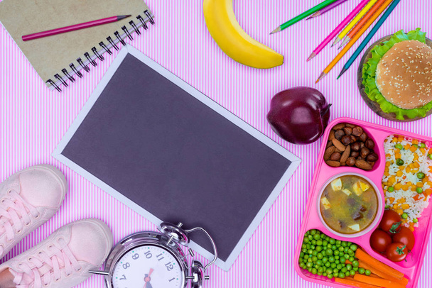 bovenaanzicht van blackboard en lade met kinderen lunch voor school op trendy violet oppervlak - Foto, afbeelding