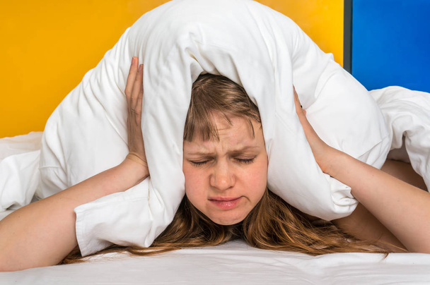 Приваблива жінка в ліжку покриває вуха подушкою через шум концепція безсоння
 - Фото, зображення