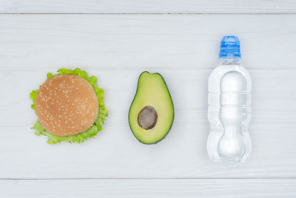 üstten görünüm Burger, avokado ve plastik şişe su ahşap tablo - Fotoğraf, Görsel