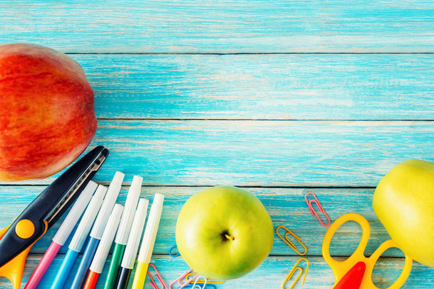 Widok z góry szkoły piśmiennicze, narzędzia pakietu office i jabłka na niebieski drewniane nackground - Zdjęcie, obraz