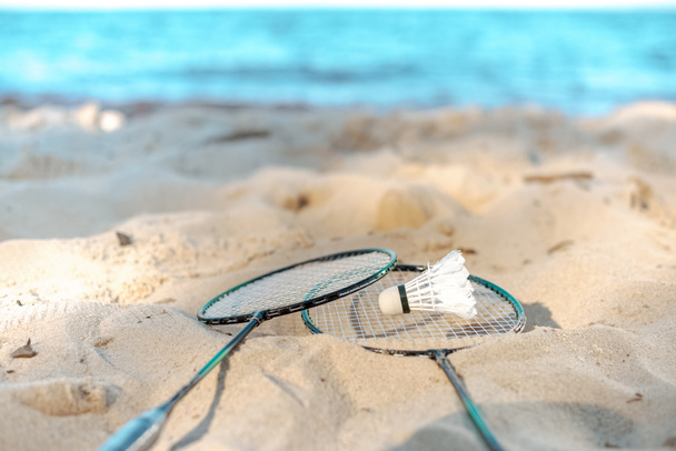 close up view of badminton racquets and shuttlecock lying on sandy beach - Fotografie, Obrázek