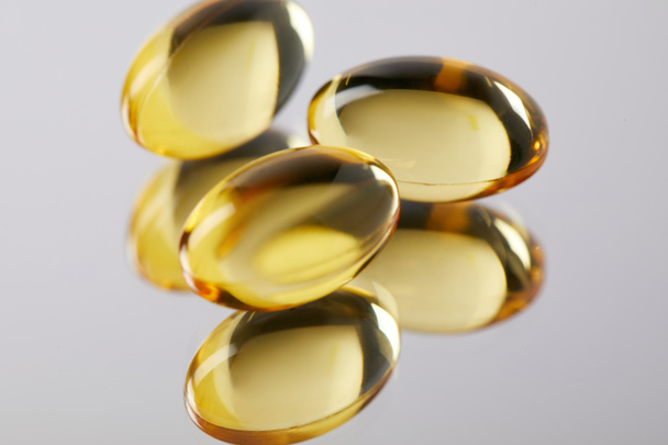 hoop van omega vis hoed supplement capsules op reflecterend oppervlak - Foto, afbeelding