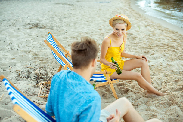 partial view of couple with beer in glass bottles resting in beach chairs on summer day - Photo, Image