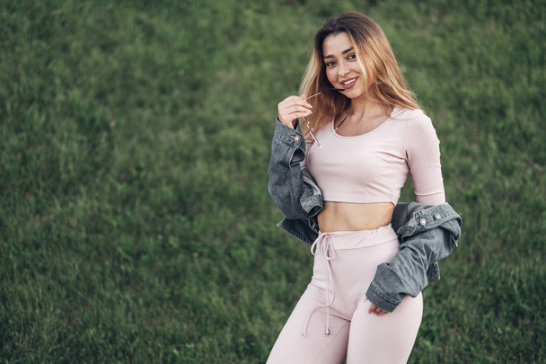 Portrait of Young and Beautiful Woman in Casual Clothes in the Street. Dressed in Pink Shirt and Pants. Spring, Summer Concept. Relax Time. Girl with Sunglasses. Enjoy City Sunset. - Foto, Imagem