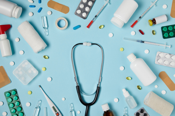 Widok z góry z stetoskop pośród różnych leków na powierzchni niebieski - Zdjęcie, obraz