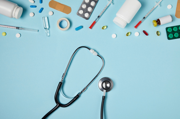 top view of stethoscope and different medicines on blue surface - Photo, Image