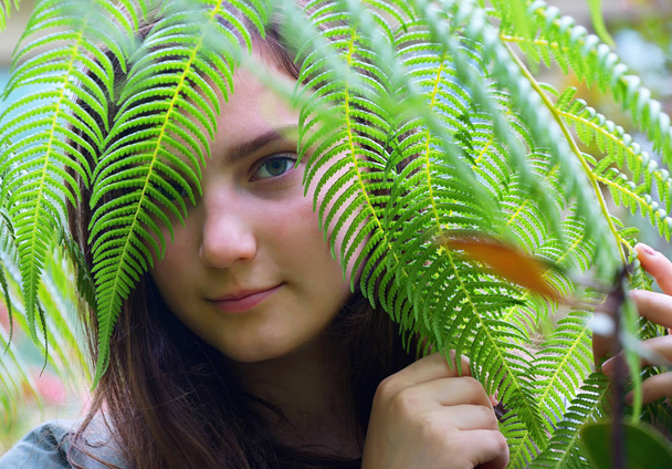 Menina adolescente assistindo através de folhas no jardim
 - Foto, Imagem
